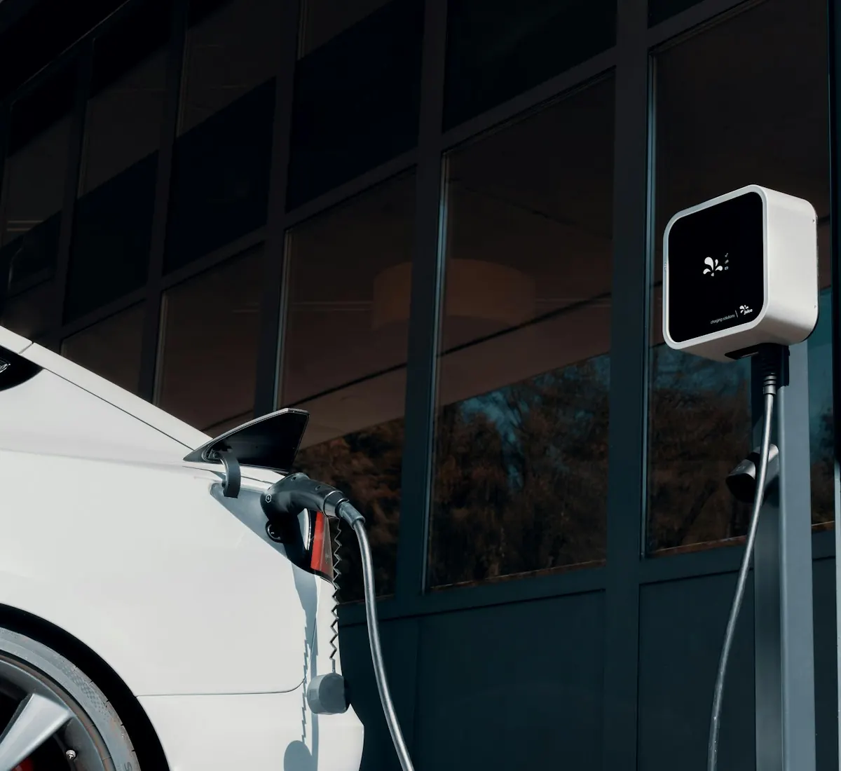 Auto eléctrico blanco cargando en un cargador de pared