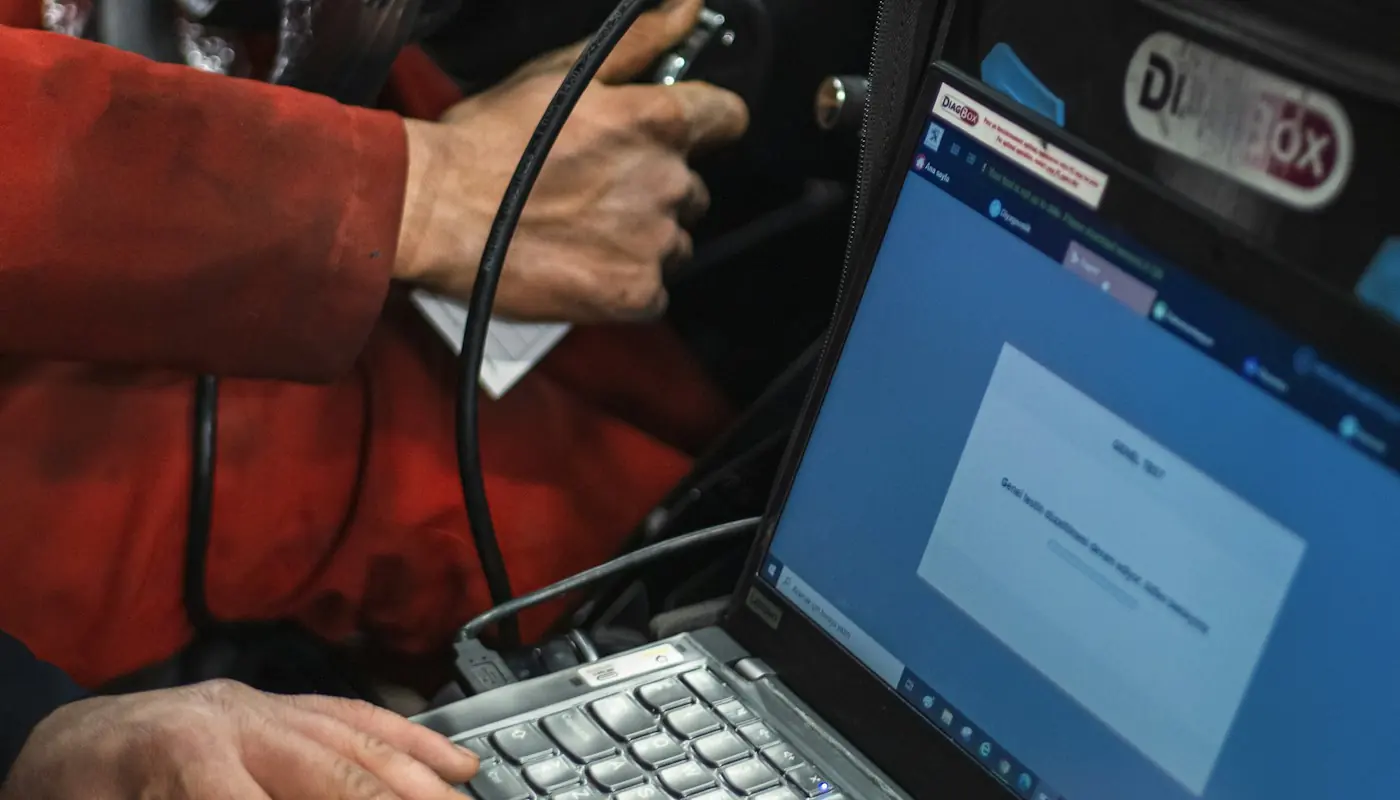Técnico conectado con una computadora para diagnosticar un auto